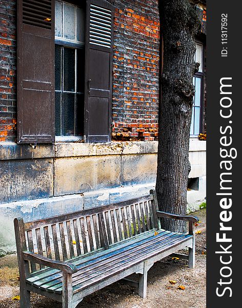 A solitary wooden bench rests next to an old building in Paris, France