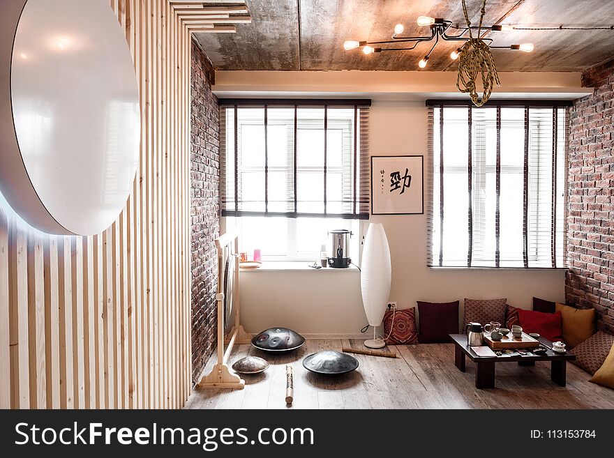 Loft room for fitness and relaxation, relaxation with brick walls and windows, gym, tea. White walls, concrete ceiling, wooden floor.