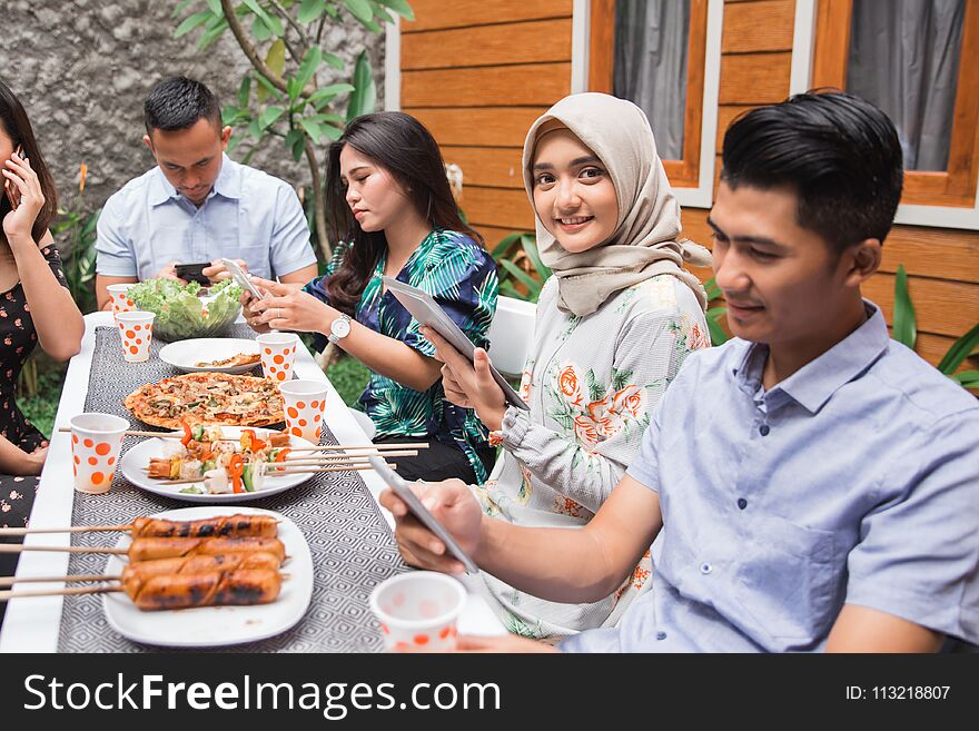 Portrait of muslim asian women looking at camera while other people focus on their own smartphone. Portrait of muslim asian women looking at camera while other people focus on their own smartphone