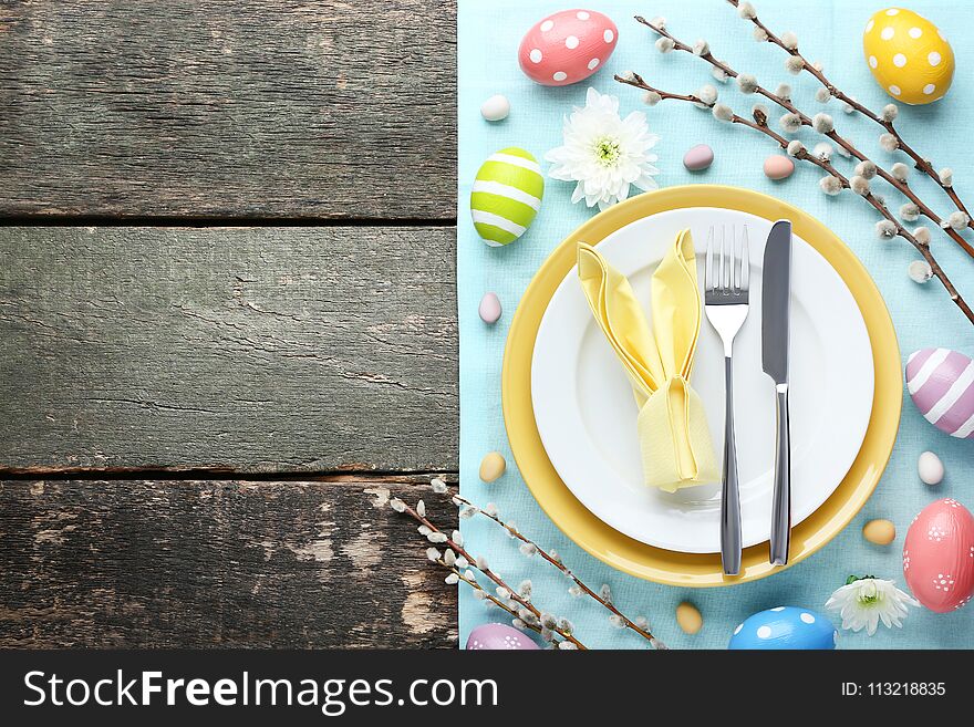 Kitchen cutlery with easter eggs and tree branches on grey wooden table