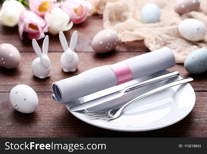 Kitchen cutlery with easter eggs and ceramic rabbits on wooden table