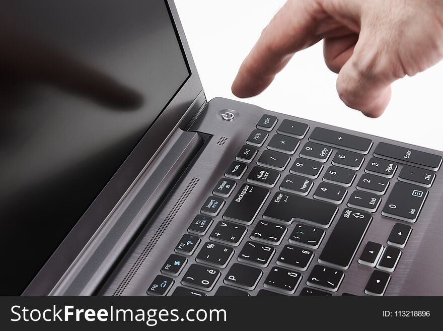 Silver laptop and moving man`s hand catching start button, on white background