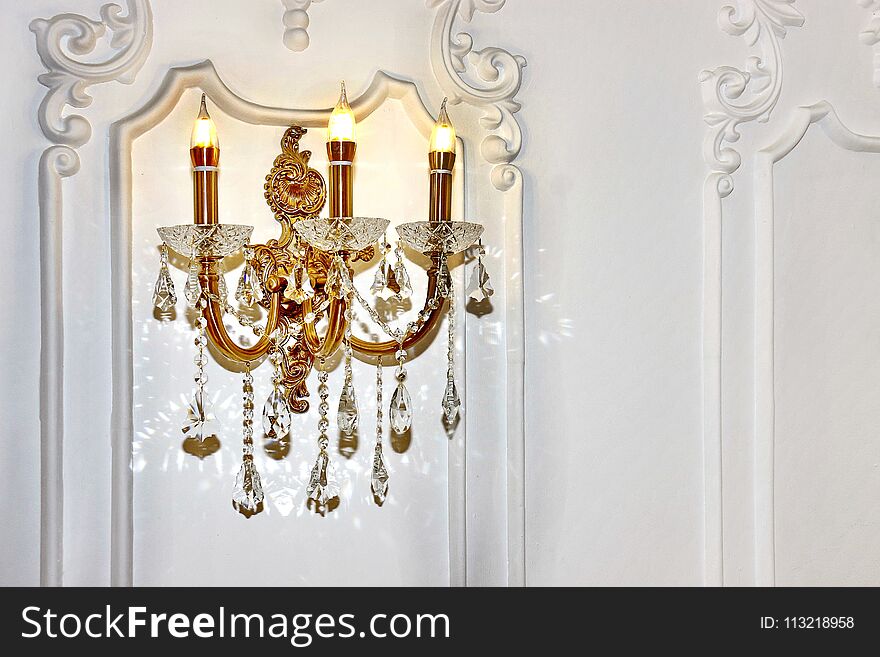 Vintage chandelier sconce lamp with candle lights on light wall, beautiful white wall light fixture