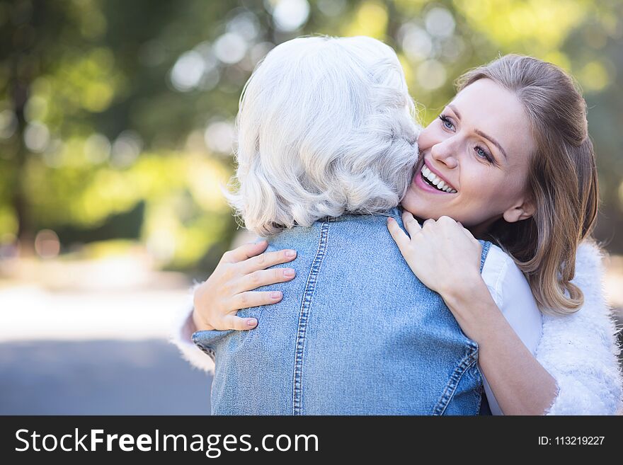 Happy young woman hugging retired mother in the park