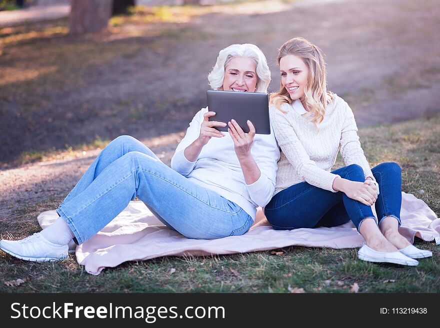 Involved woman enjoying picnic with aged mother in the park