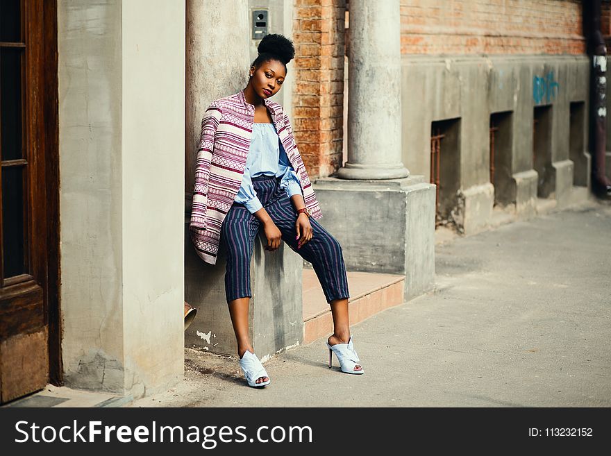 Woman Sitting on Gray Concrete Pillar