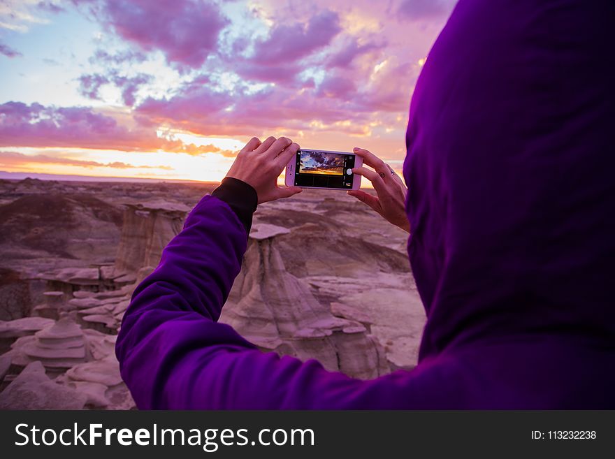 Person Wearing Purple Hoodie Jacket Holding Iphone 6 during Golden Hour