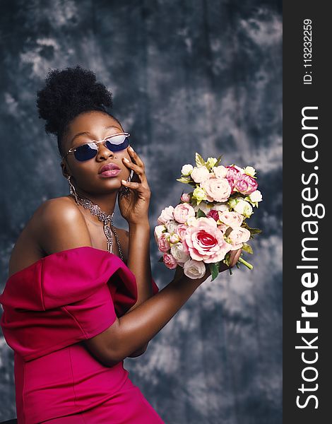 Woman Wearing Sunglasses and Posing for Pic With Flowers