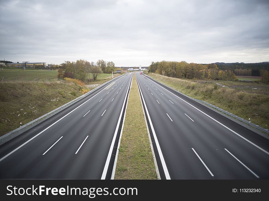 Two Grey Concrete Roads Between Green Grasses