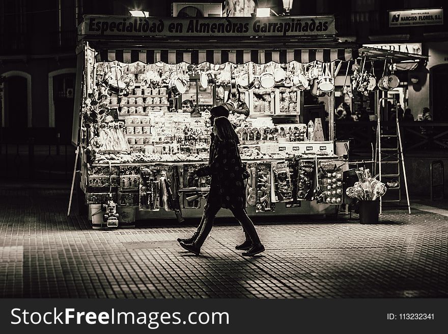Man and Woman Walking in Front of Store Greyscale Photo