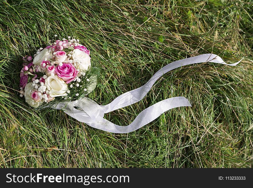 Romantic fresh colorful wedding bouquet of roses on green grass with white textile lace and smal cute flowers in summer day. Romantic fresh colorful wedding bouquet of roses on green grass with white textile lace and smal cute flowers in summer day