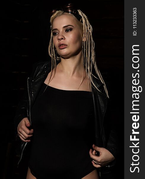 blonde beautiful woman with dreadlocks on a dark background in the studio