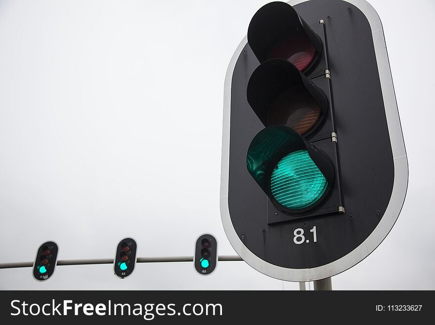 Closeup of green traffic lights and overcast sky