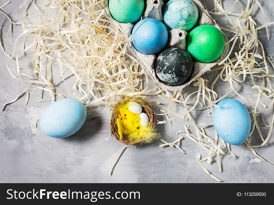 Painted eggs in tray, chicken eggs, paint and brush on concrete surface, Easter decorations.