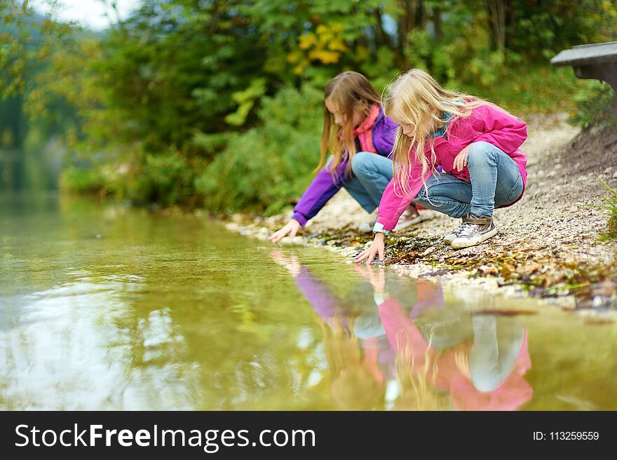 Two little girls enjoying the view of wonderful green waters of Hintersee lake. Amazing autumn landscape of Bavarian Alps on the A