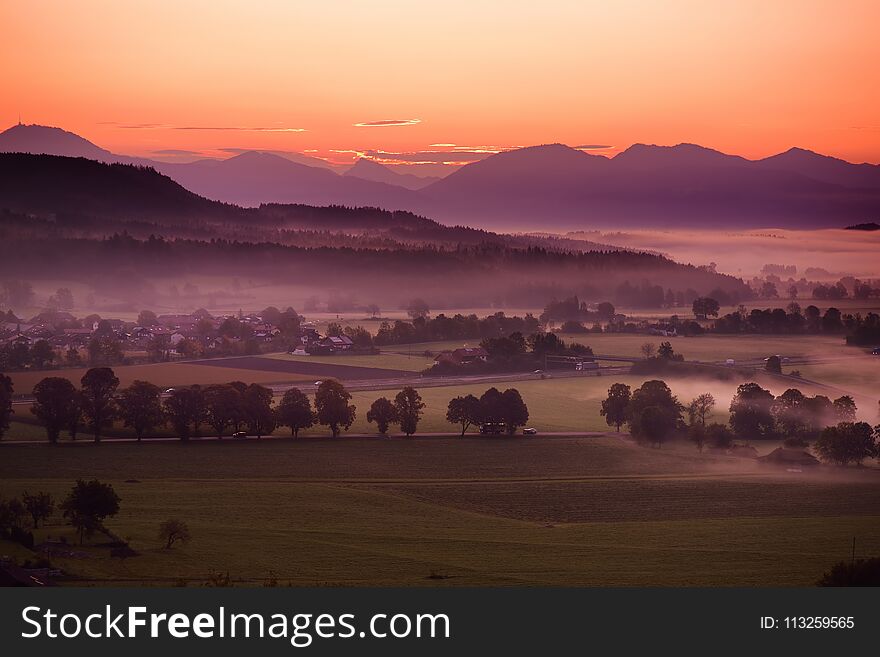 Breathtaking morning lansdcape of small bavarian village covered in fog. Scenic view of Bavarian Alps at sunrise with majestic mou