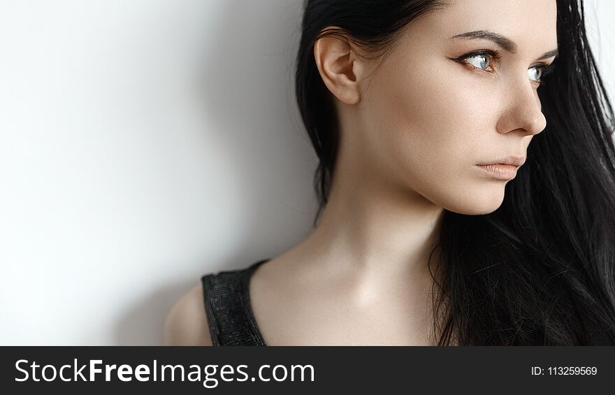 Girl with black hair looking away from behind a white wall. Girl with black hair looking away from behind a white wall
