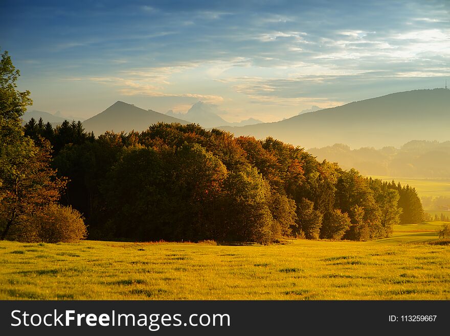 Breathtaking lansdcape of Austrian countryside on sunset. Dramatic sky over idyllic green fields of Anstrian Central Alps on autum