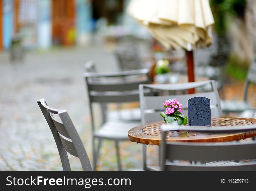 Empty outdoor cafe on beautiful rainy autumn day in Lindau, Germany. Empty chiars and tables under falling rain in autumn.