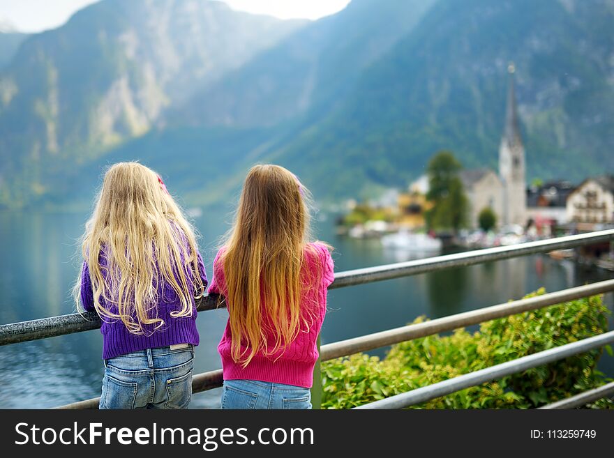 Two girls enjoying the scenic view of Hallstatt lakeside town in the Austrian Alps in beautiful evening light on beautiful day in