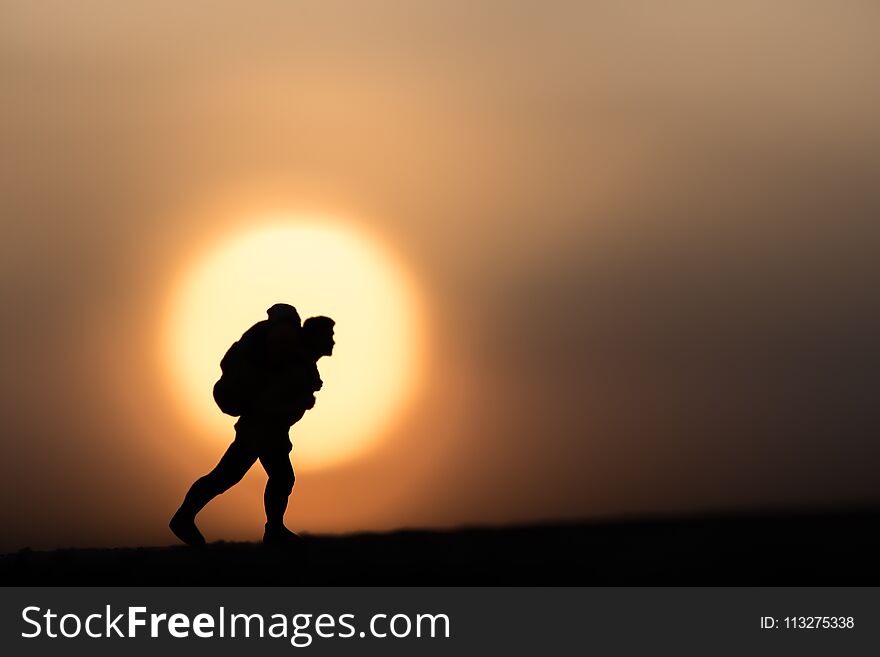 Silhouette traveler backpacker alone on a sunset background.