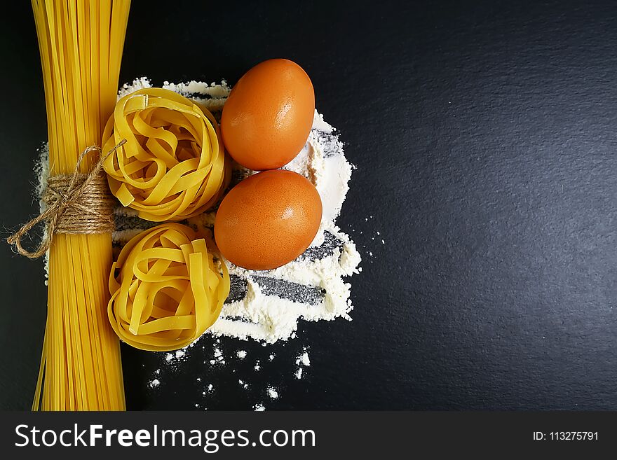 Different Kinds Of Pasta Tagliatelle, Spaghetti, Italian Foods Concept And Menu Design, Raw Eggs And Flour On A Shale Board, Empty