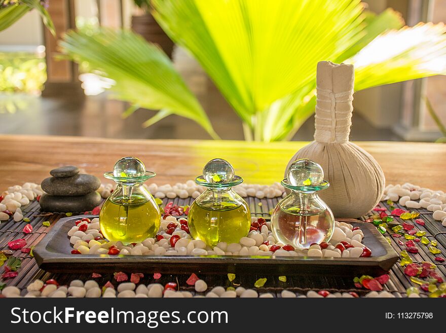 Three glass bottles with aromatic scent and spice on the wooden table at the SPA