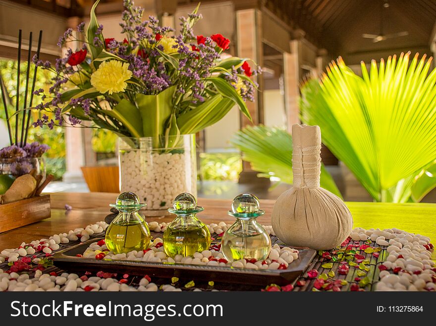 Three glass bottles with aromatic oil and flowers on the wooden table at the SPA