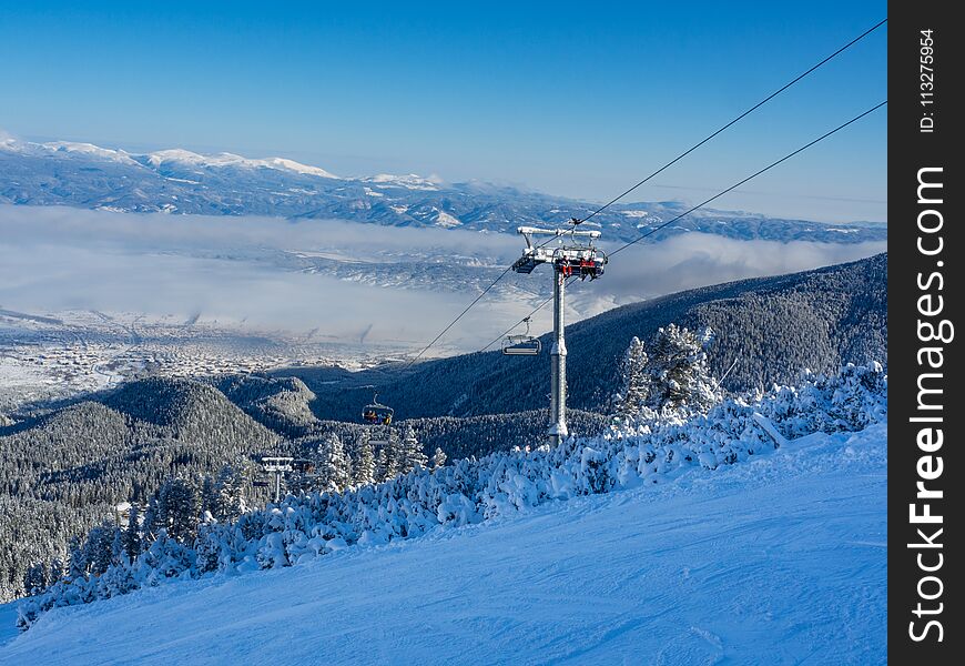 Cable car cabin in Bansko, Bulgaria and snow mountain peaks at the background. Blue sky, 2017