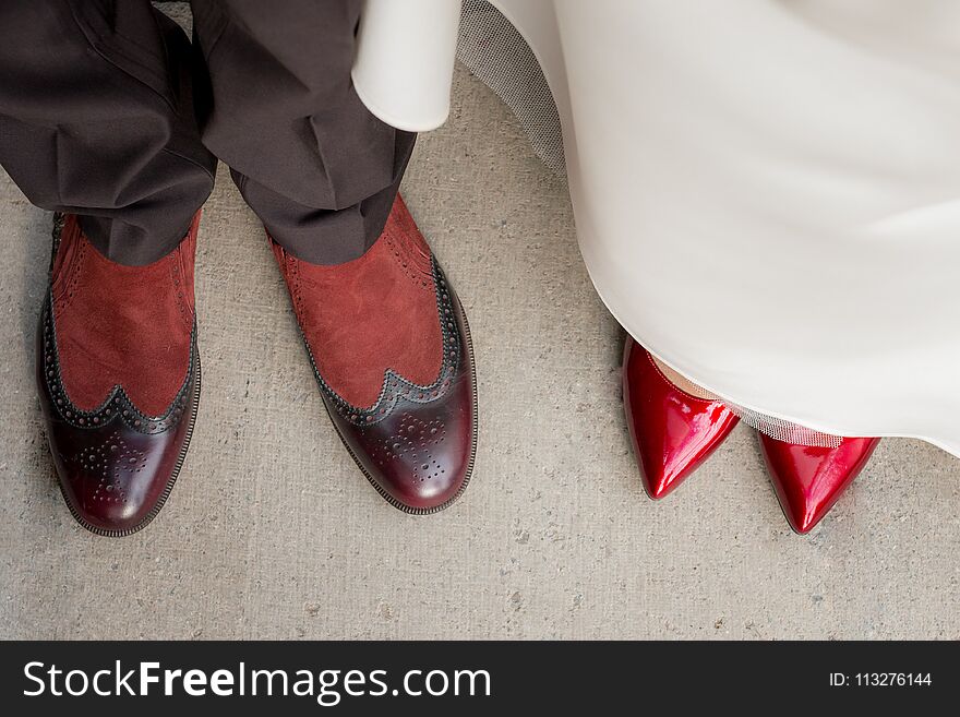 Top view of groom s and bride s legs in stylish shoes on the background of green grass
