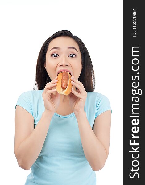 Excited Asian young woman devouring tasty hot dog. Excited Asian young woman devouring tasty hot dog
