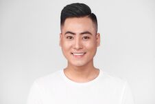 Portrait Of Handsome Young Asian Man Against Grey Background Stock Photo