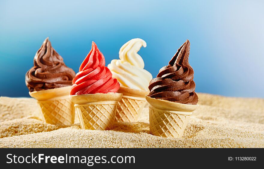 Colourful ice cream in crunchy cones stuck into sand. Colourful ice cream in crunchy cones stuck into sand