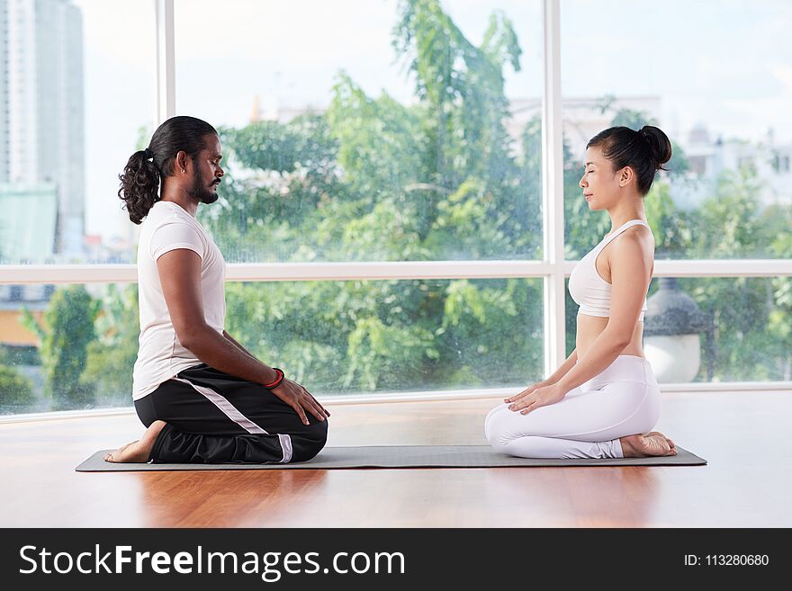 Meditating couple on yoga mat in fitness club