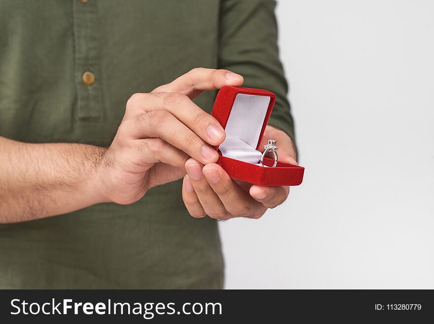 Close Up Of Male Hands Holding Wedding Ring And Gift Box.