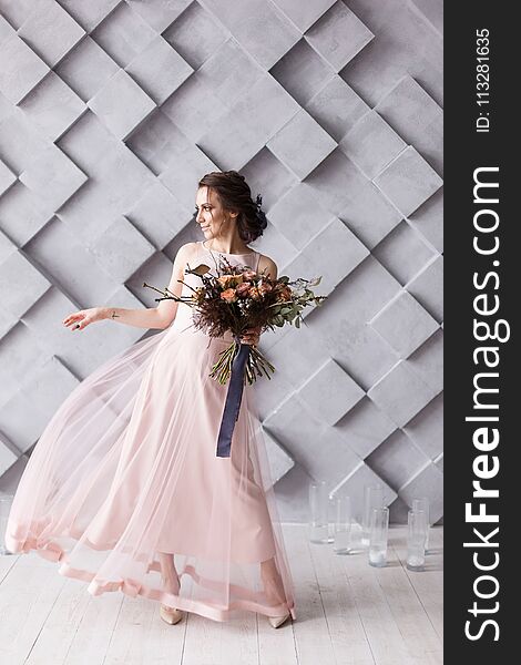 Young bride with coloful bouquet on modern gray geometric background.