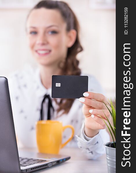 Close up of credit card in pretty young woman`s hand. Girl shopping online at table. E-business concept. Close up of credit card in pretty young woman`s hand. Girl shopping online at table. E-business concept