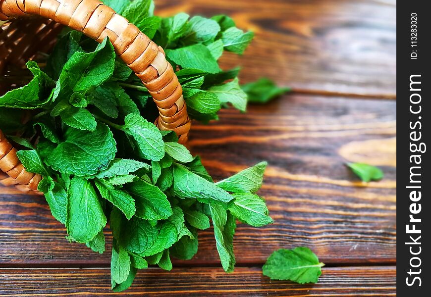 Bunch Of Mint In A Small Wicker Basket On Old Burnt Wooden Background