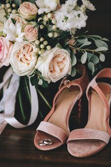 Wedding Velvet Pink Shoes With Gold Wedding Rings Beside A Bouquet Of White Roses, Eucalyptus On A Dark Wooden Background Royalty Free Stock Photography