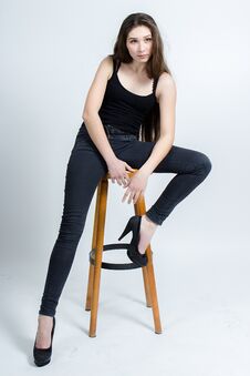 Girl With Long Dark Hair Posing On Chair, Black Tank Top Jeans Royalty Free Stock Photography
