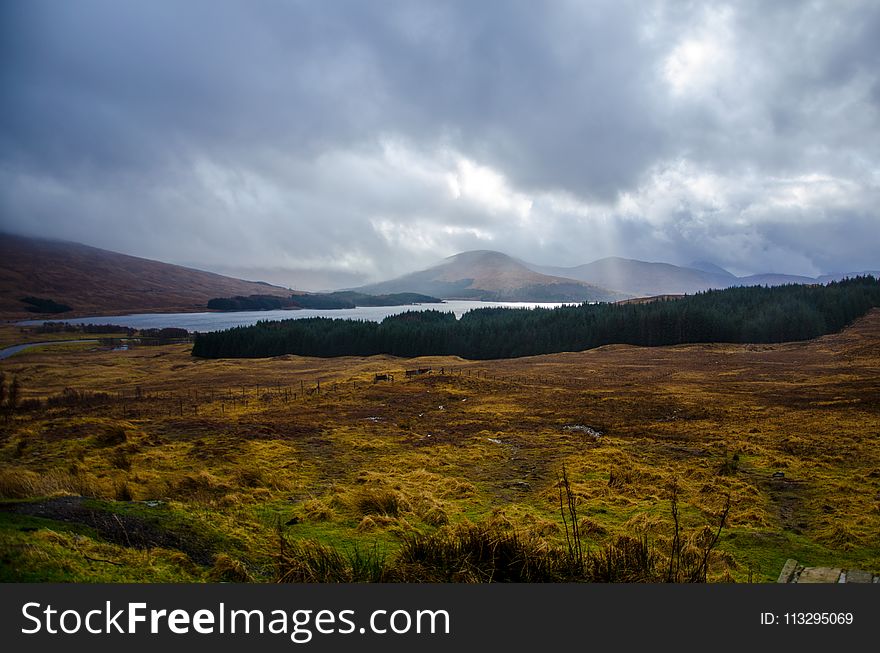 Mountain Beside Body Of Water Under White Clouds