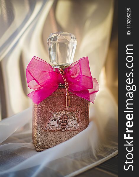 Close Photograph Of Glitter Pink Fragrance Bottle With Red Ribbon