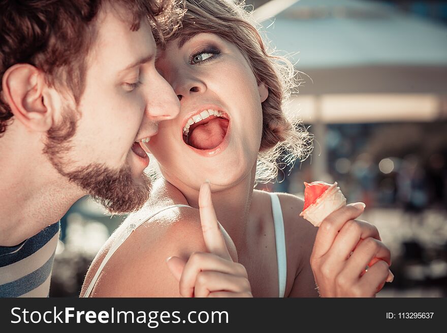 Summer holidays and happiness concept. Young couple eating ice cream outdoor in the city