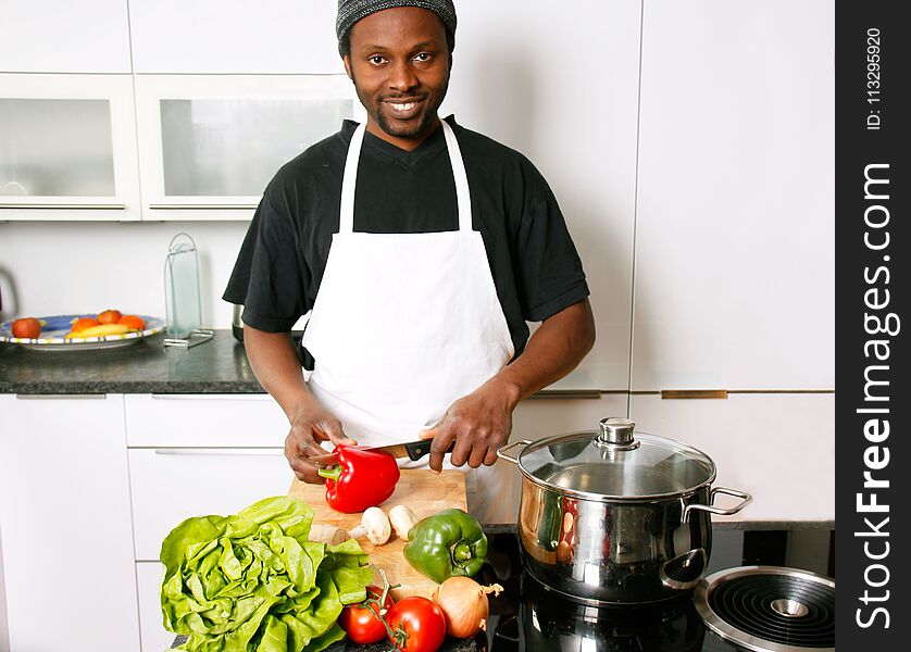 A young smiling, happy chef cooking in the kitchen with passion. A young smiling, happy chef cooking in the kitchen with passion