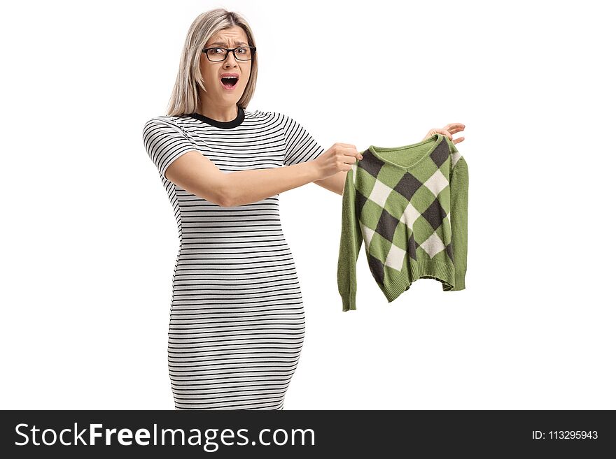 Shocked young woman holding a shrunken blouse and looking at the camera isolated on white background
