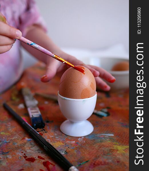 The Traditional Eastern - The egg is being painted by a brush in hands of a little czech girl.