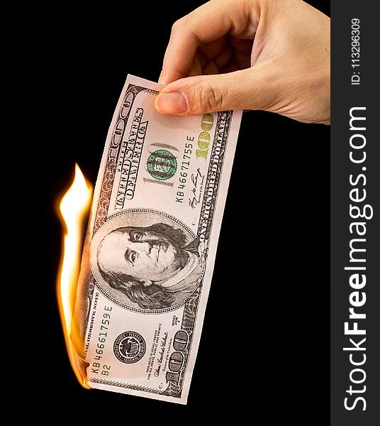 One hundred dollars burn in the hand on a black background