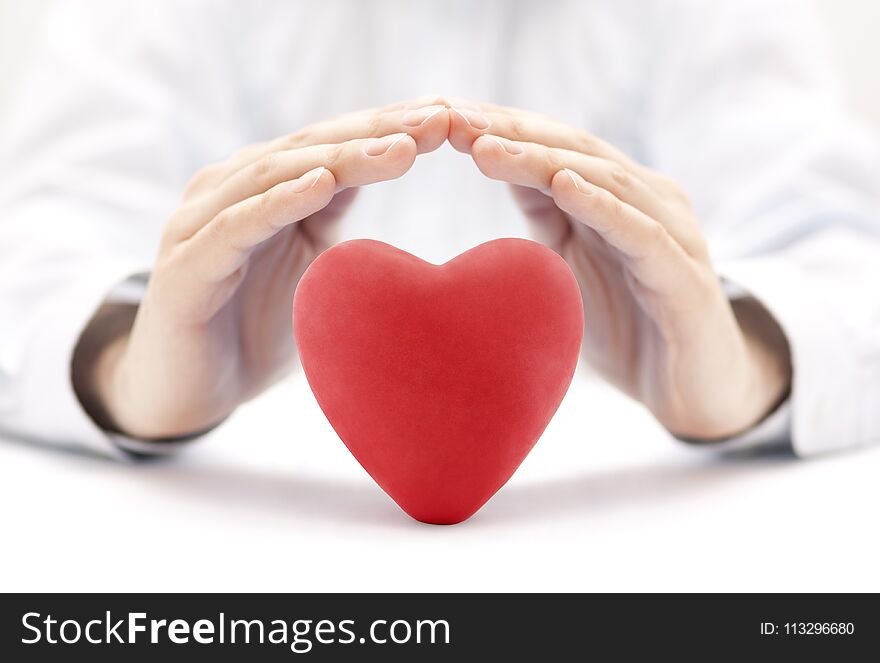 Red heart covered by hands. Health insurance or love concept