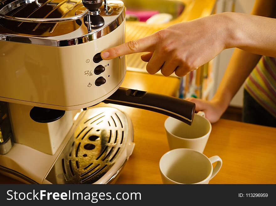 Homemade drinks concept. Woman making hot drink in coffee machine standing in kitchen.