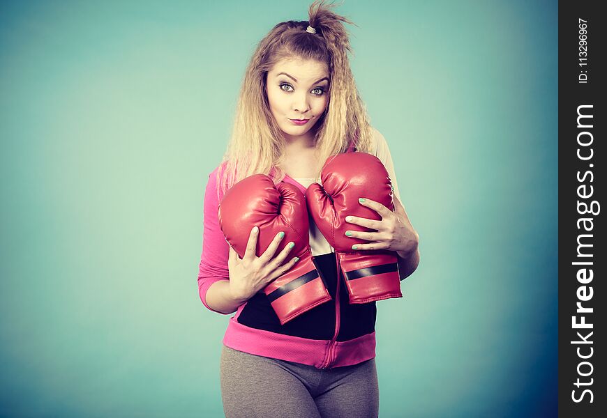 Funny cute blonde girl female boxer with big fun red gloves playing sports boxing studio shot on blue. Funny cute blonde girl female boxer with big fun red gloves playing sports boxing studio shot on blue